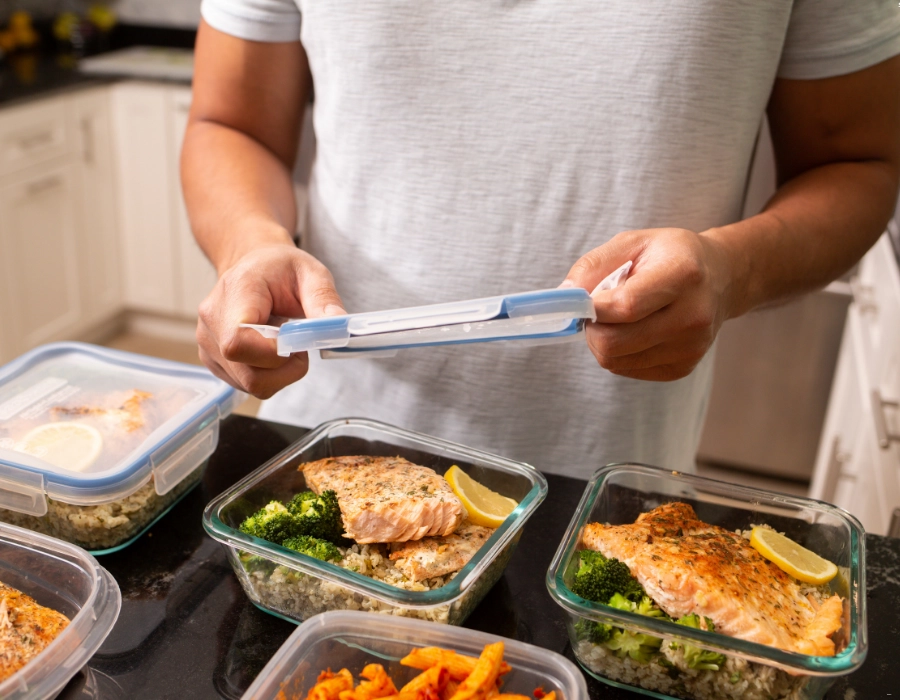 Meal prep med färdiglagade portioner av lax, ris och broccoli i matlådor.