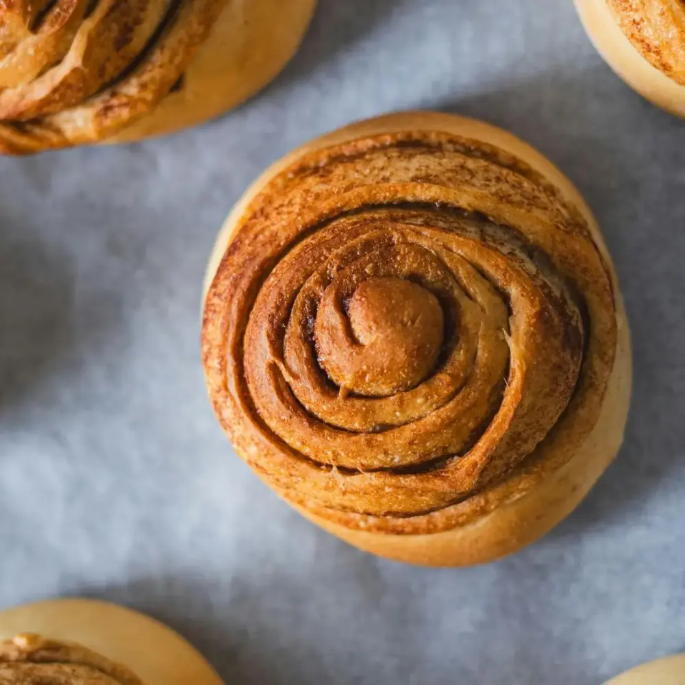 Nybakade kanelbullar på bakplåtspapper inför Kanelbullens dag.